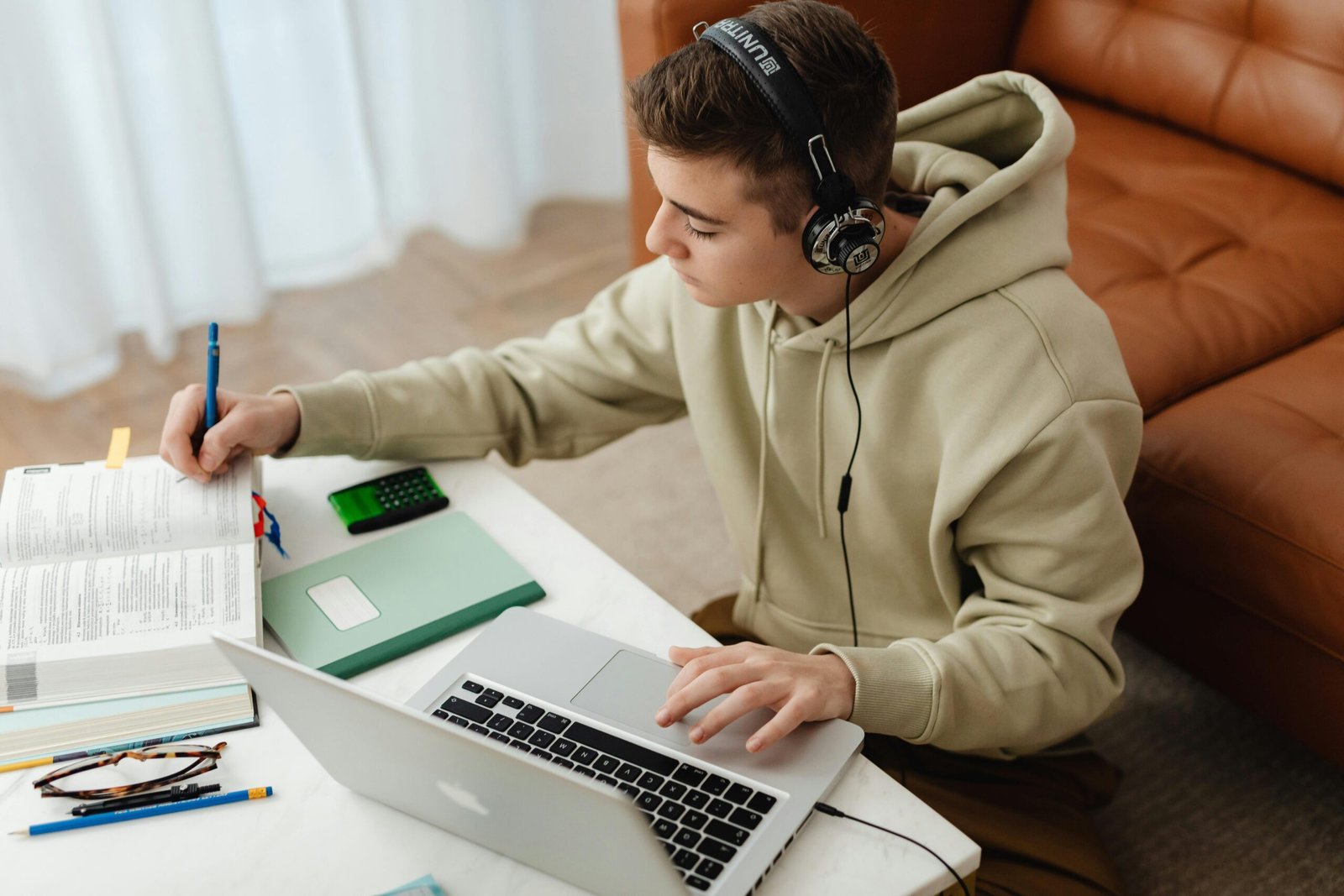 Photo of a teenager proudly holding a piggy bank next to her laptop