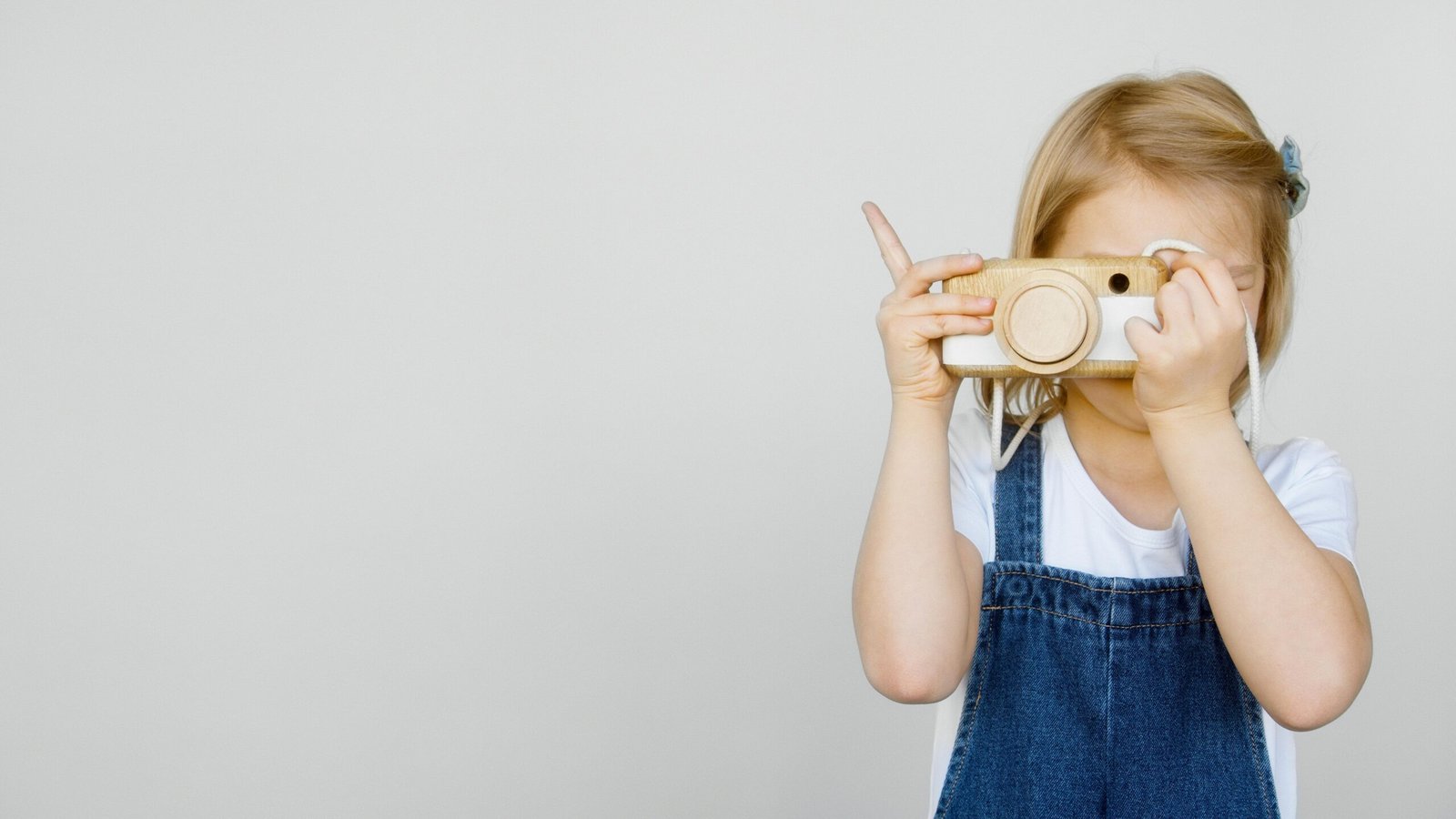 Photo of a young girl smiling while holding coins next to her piggy bank