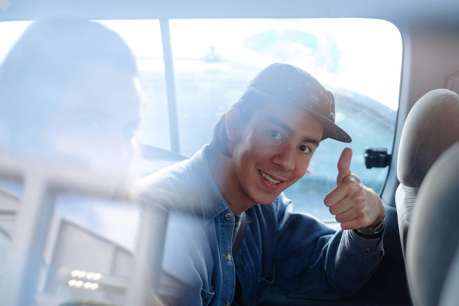 A confident teenager smiling while holding coins near a savings jar labeled 'Dream Car Fund'