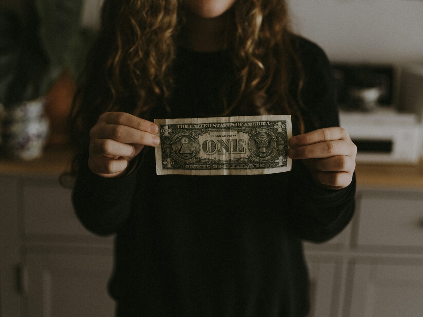 A teenager holding an empty wallet while surrounded by receipts.